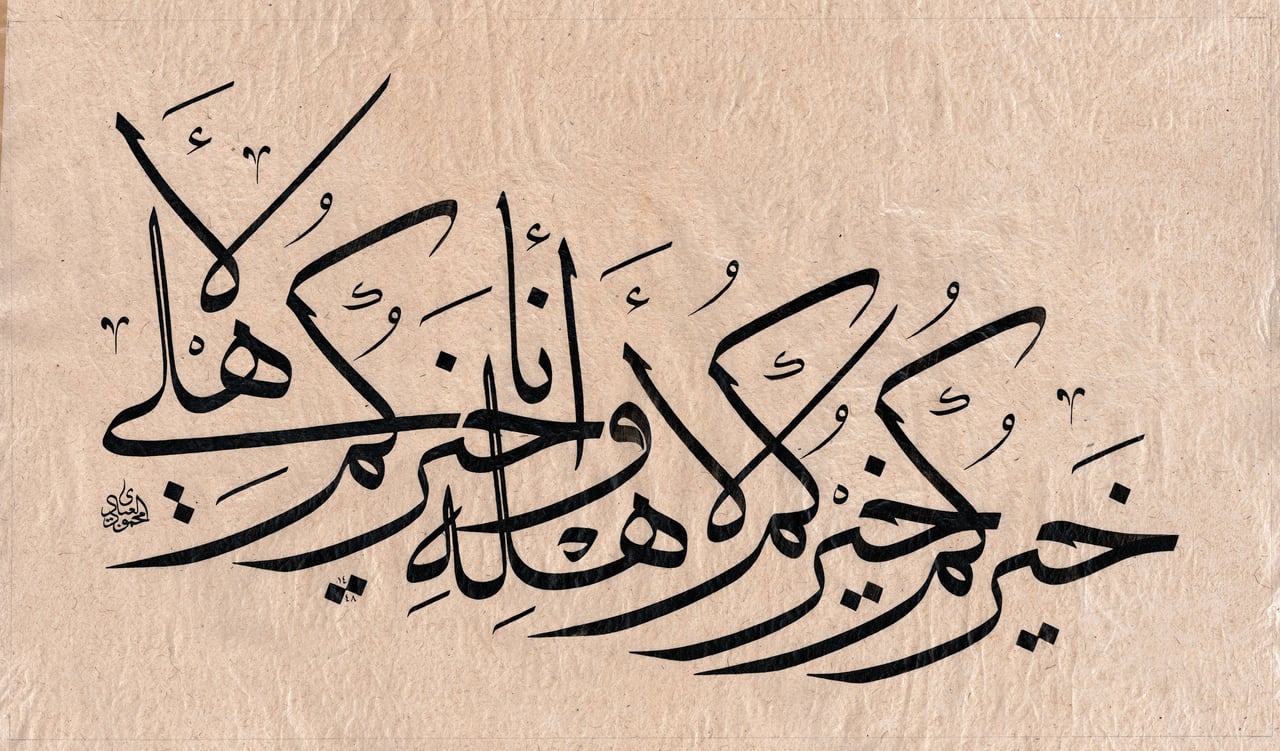 سطر صاعد من خط المحقّق بالحبر الأسود على ورق مقهّر فاتح