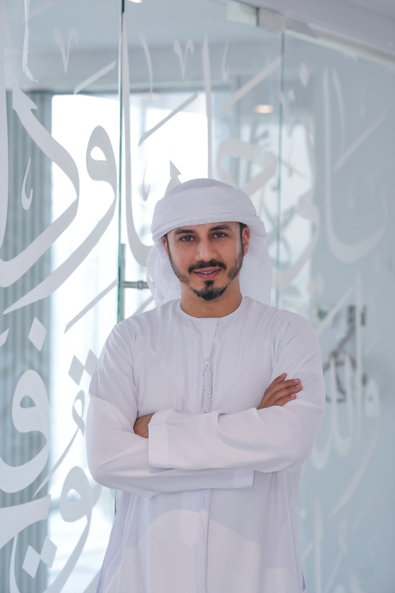 محمود العبادي واقفاً أمام الزجاج المكتوب